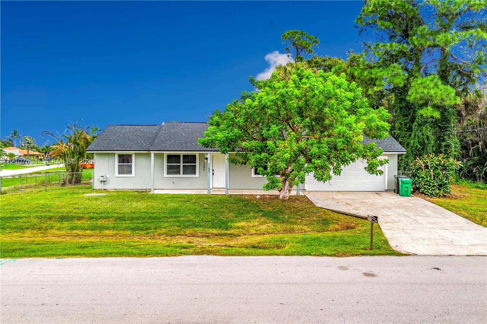 1131 SW London Lane, Port St Lucie, FL 34953 Single-story home with a clean white exterior and covered front entry