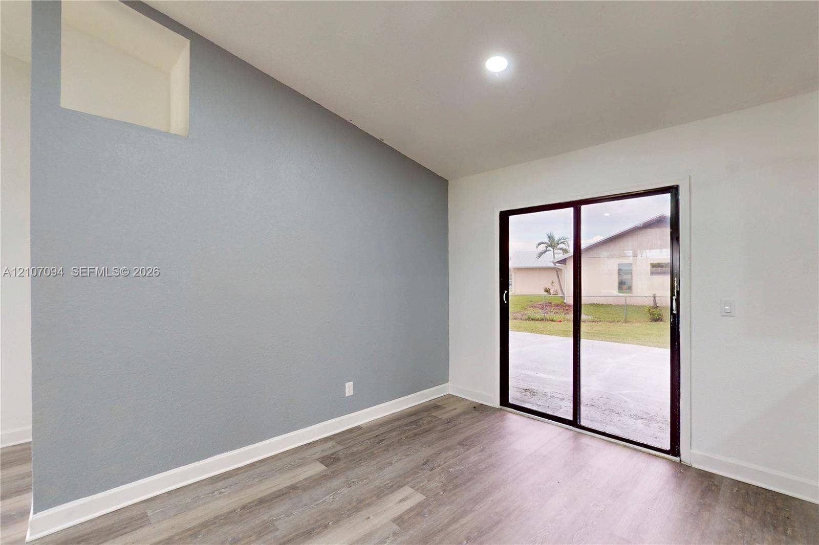 1131 SW London Lane, Port St Lucie, FL 34953 Sloped ceiling with recessed lighting, wood-finish flooring, accent wall, and sliding glass door