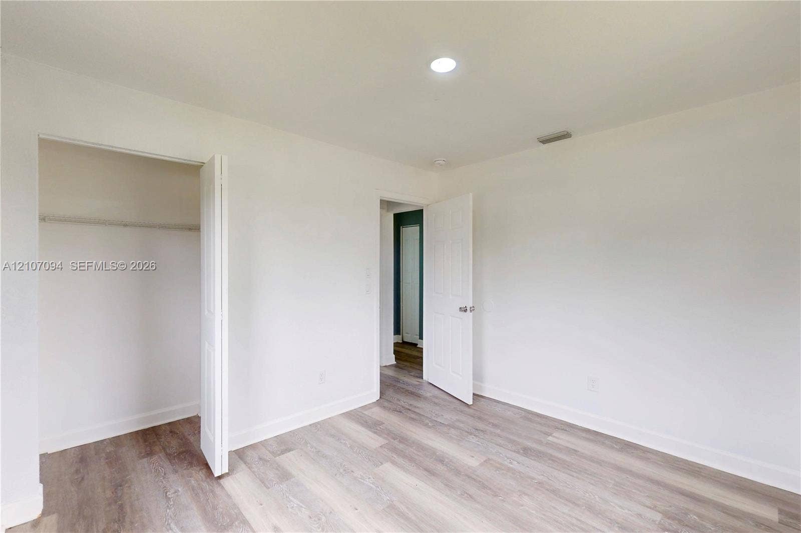 1131 SW London Lane, Port St Lucie, FL 34953 Interior space featuring wood-finish flooring, white walls, recessed ceiling lighting, and a closet with a bi-fold door