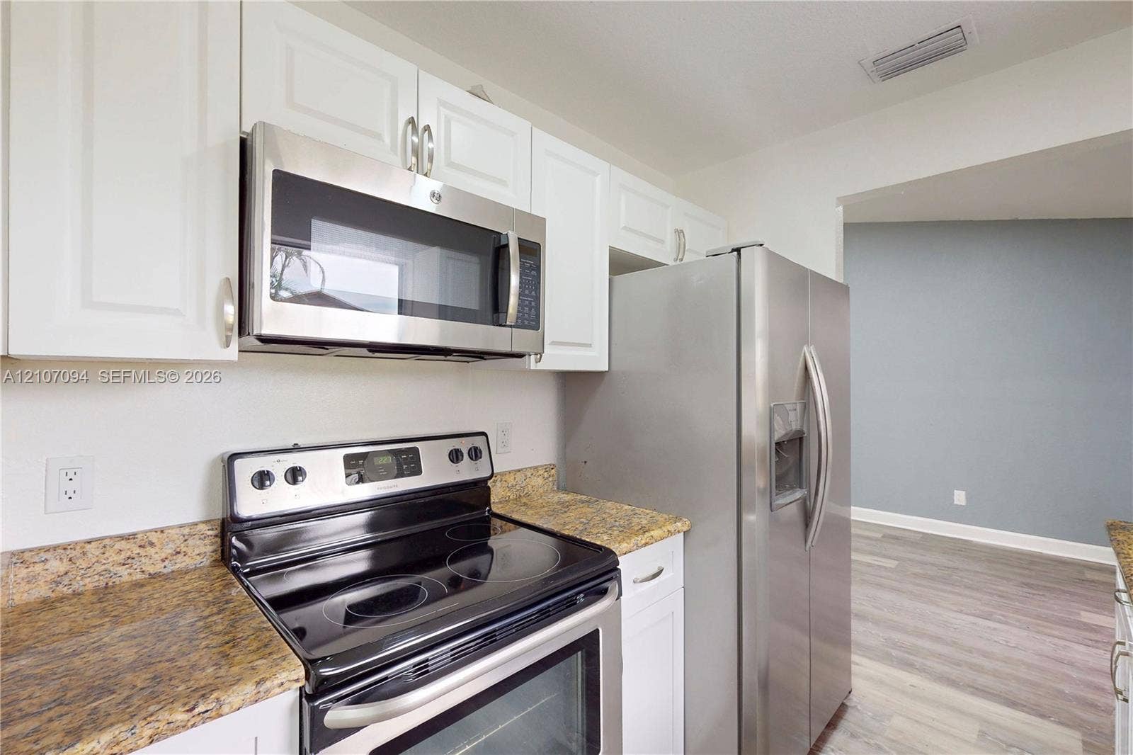 1131 SW London Lane, Port St Lucie, FL 34953 Kitchen featuring white cabinetry, stainless steel appliances, and stone-finish countertops