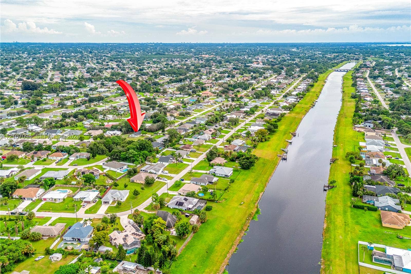1131 SW London Lane, Port St Lucie, FL 34953 Aerial perspective of residential parcel featuring mature trees and canal frontage