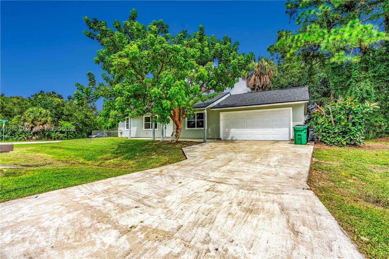 1131 SW London Lane, Port St Lucie, FL 34953 Single-story exterior featuring a concrete driveway, two-car garage, and mature trees on a landscaped lot