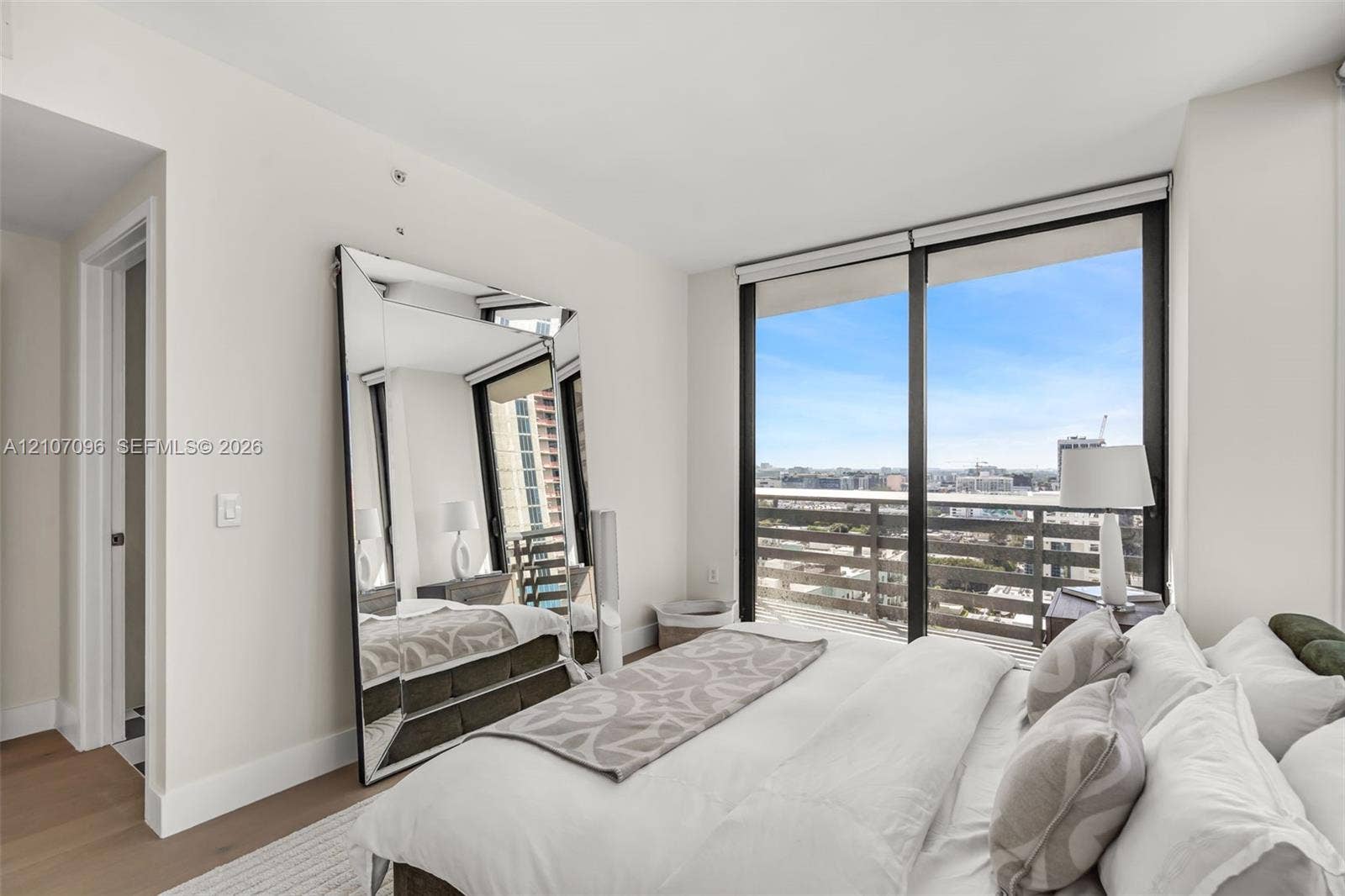 Floor-to-ceiling windows, wood-finish flooring, and private balcony with metal railing