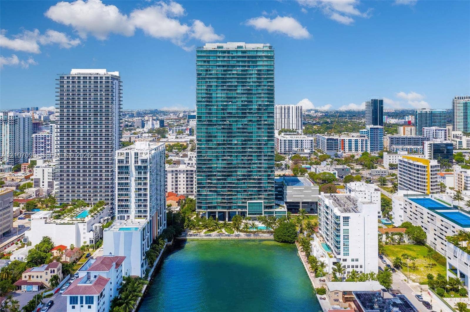 High-rise building featuring a glass facade, private balconies, and waterfront positioning