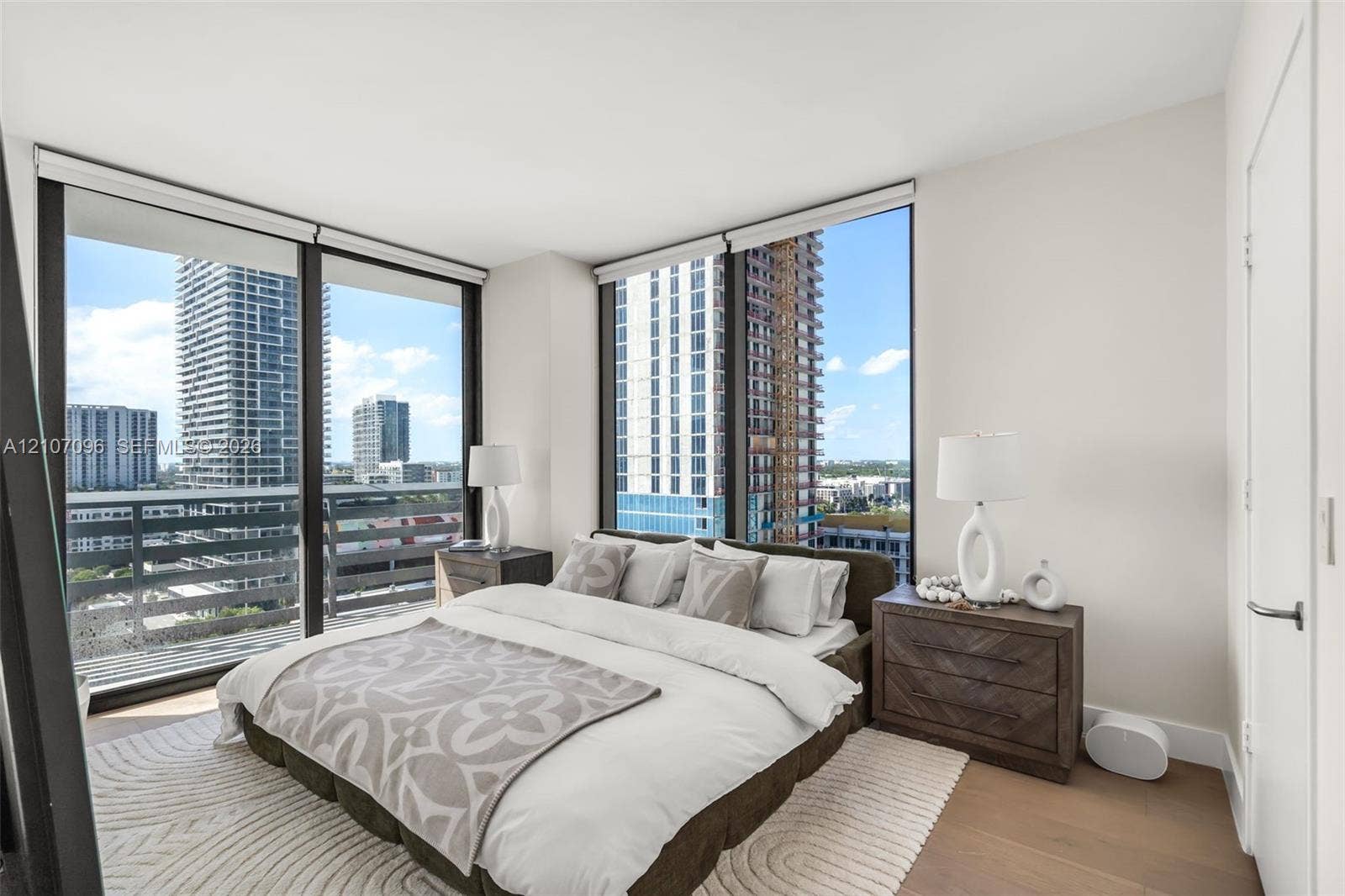 Floor-to-ceiling windows, wood-finish flooring, and metal-framed balcony railing