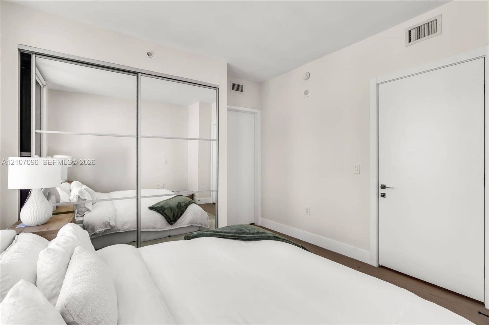 Floor-to-ceiling sliding mirrored closet doors, solid core interior door, and neutral wall finish