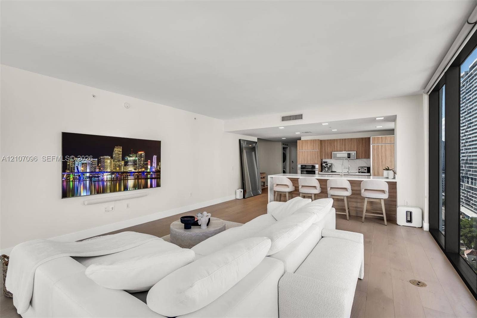 Open-concept living space with wood-finish flooring, floor-to-ceiling windows, and recessed lighting