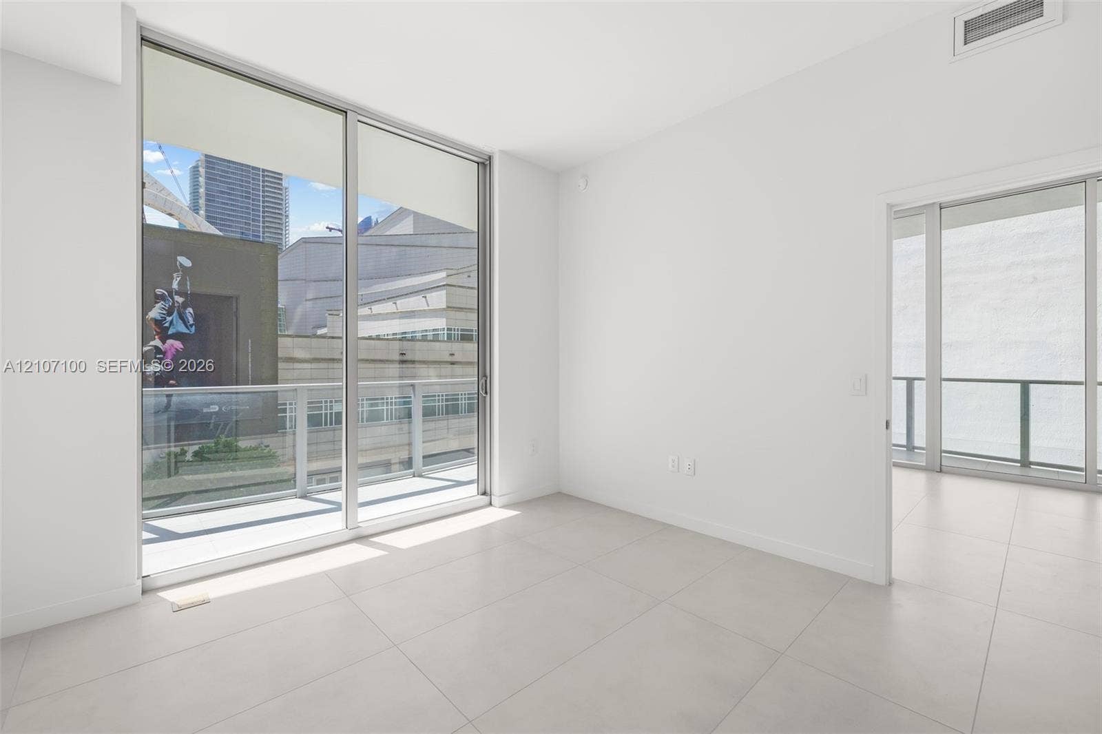 Interior space featuring large-format tile flooring, floor-to-ceiling glass sliding doors, and access to private balcony areas with metal railings