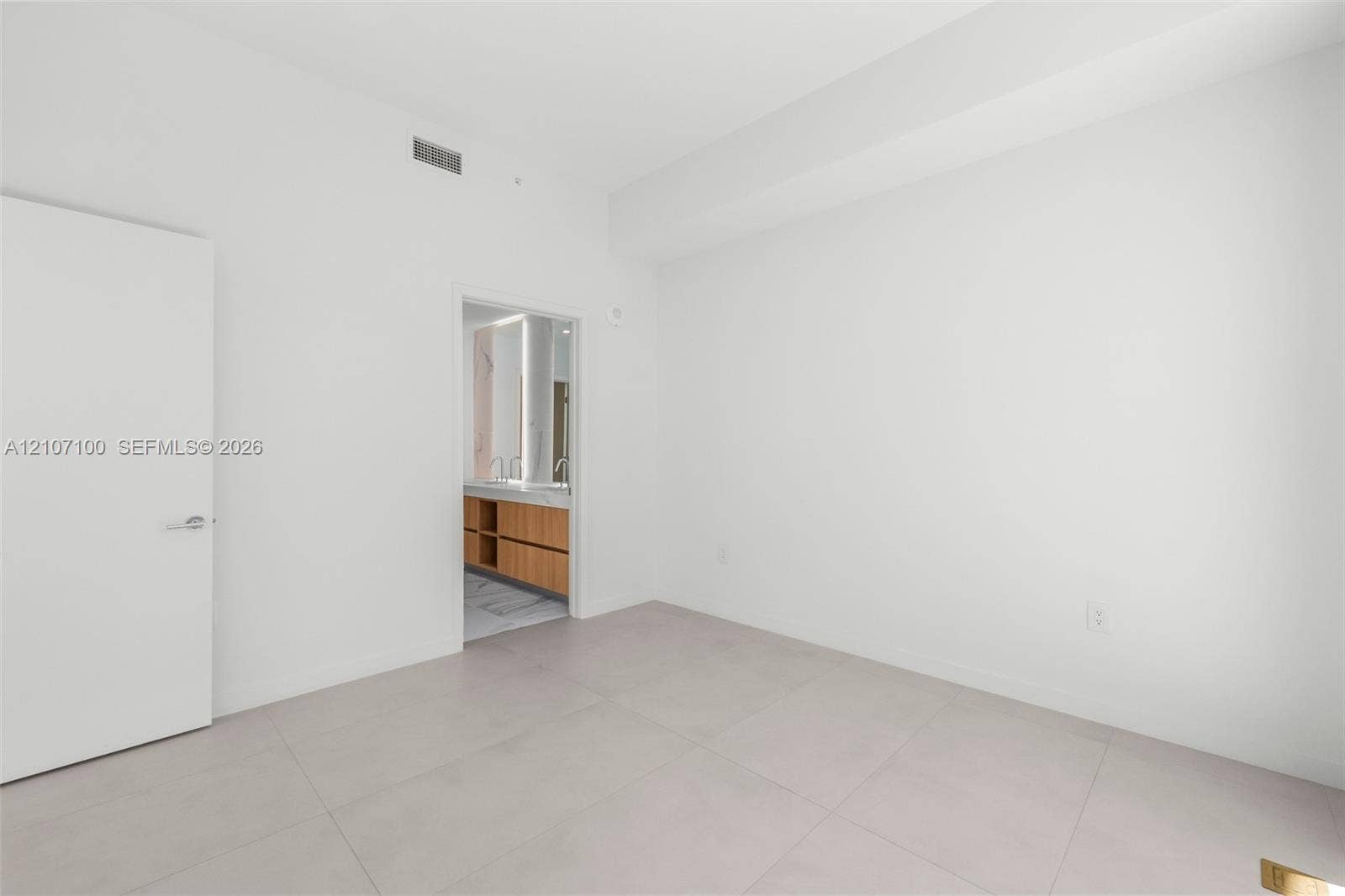 Minimalist interior featuring large-format ceramic tile flooring, smooth wall finish, and a solid-core interior door