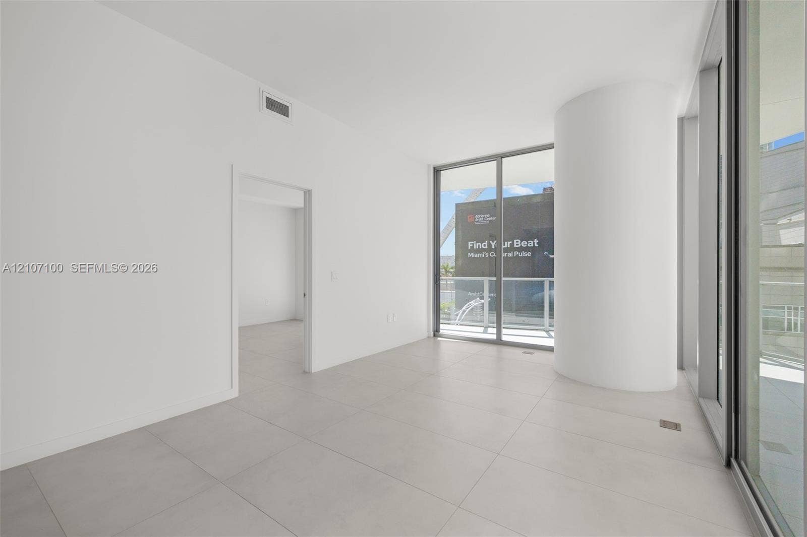 Open interior featuring large-format tile flooring, floor-to-ceiling glass sliding doors, and a curved architectural column