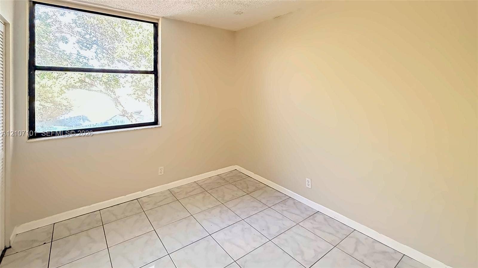 Room featuring large window with black frame, neutral wall color, and square-tile flooring