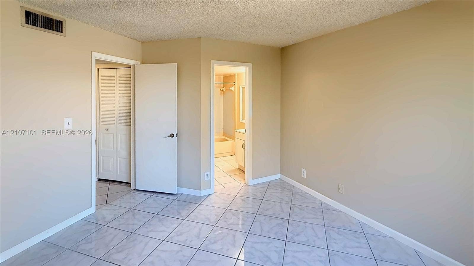 Interior room featuring neutral wall paint, diagonal tile flooring, and louvered bifold closet doors