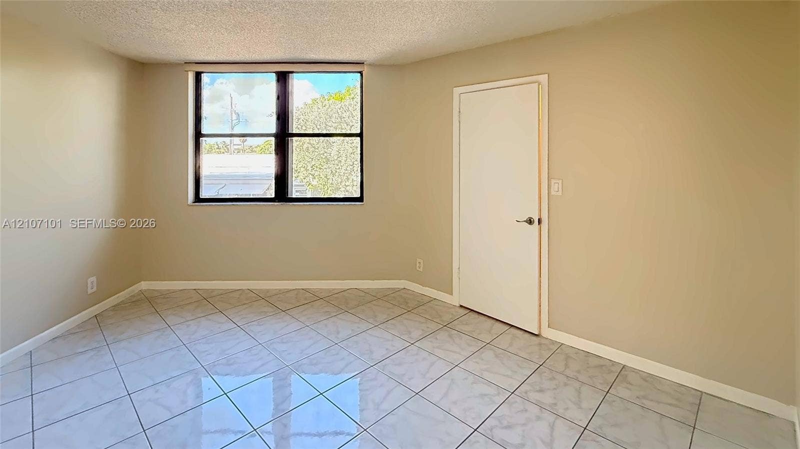 Room featuring light-toned tile flooring, neutral wall paint, and a single-pane window with dark framing