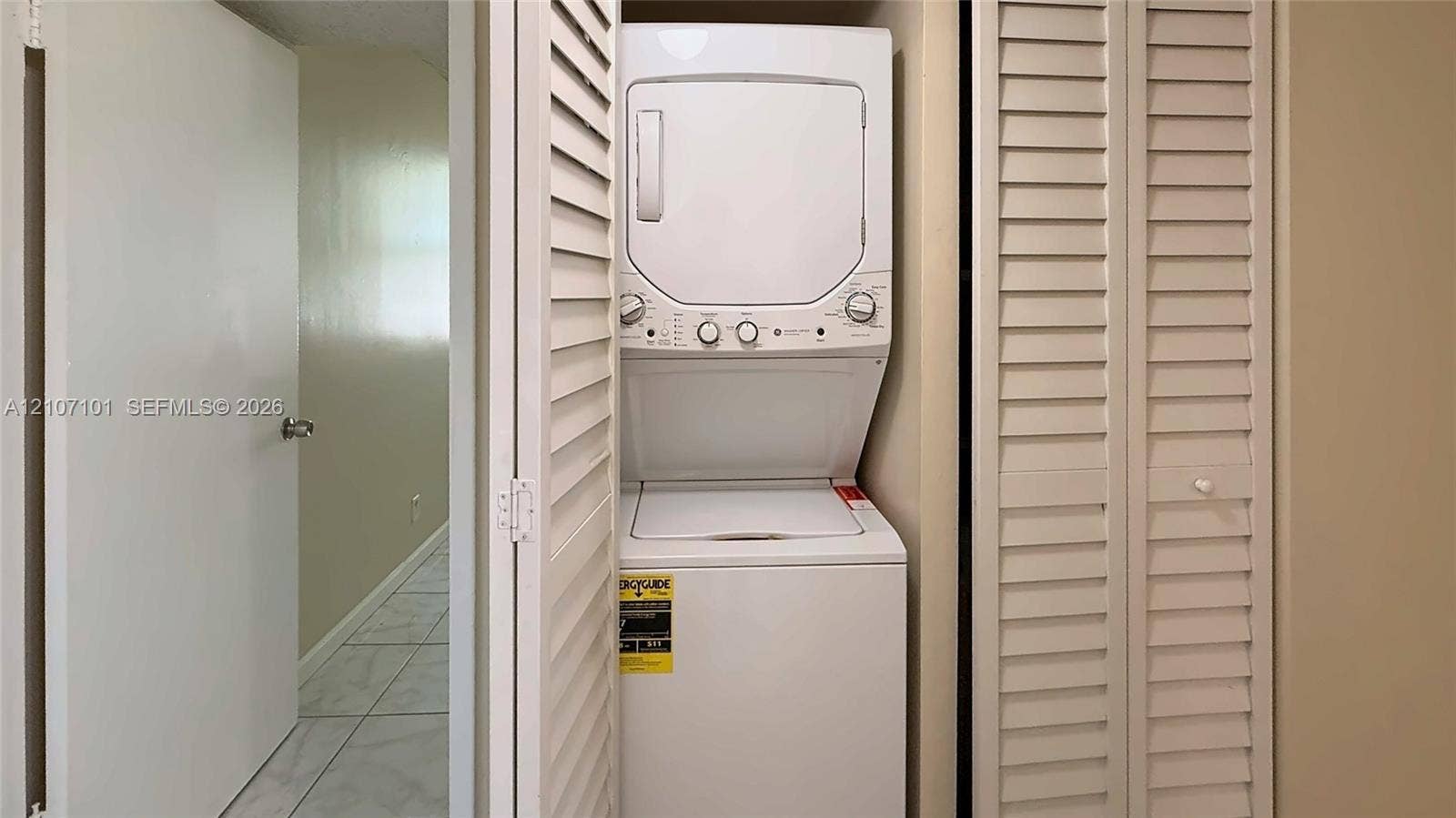 Stackable laundry unit housed within a closet featuring dual louvered doors