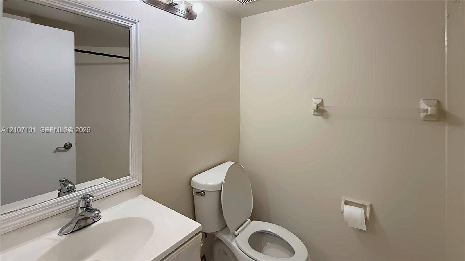 Bathroom featuring a vanity with an integrated sink, polished chrome faucet, framed mirror, and wall-mounted light fixture