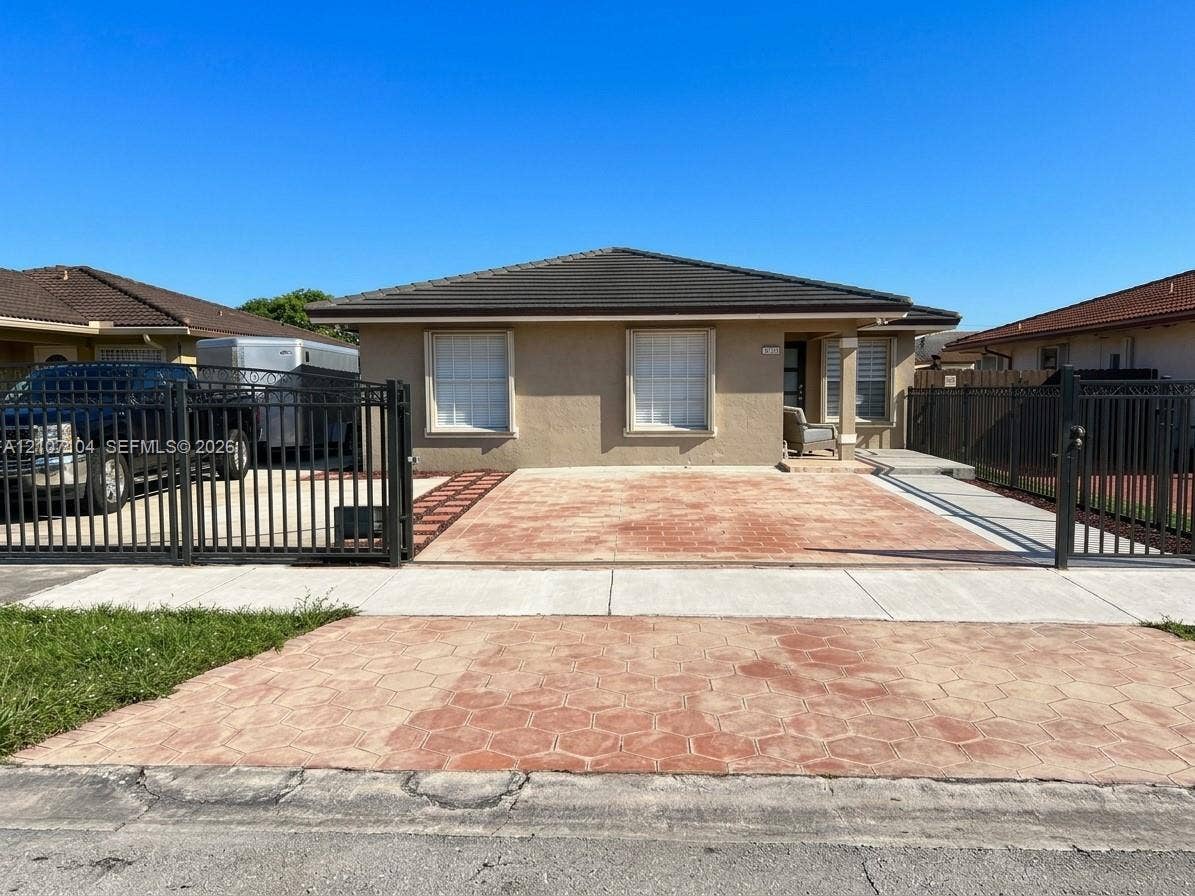 16259 SW 306th Street, #0, Homestead, Homestead, FL 33033 Single-story residence featuring a low-slope roof, stucco exterior, stamped concrete driveway, and a metal perimeter fence