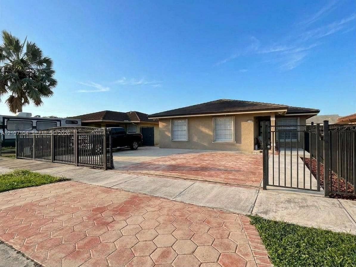 16259 SW 306th Street, #0, Homestead, Homestead, FL 33033 Single-story residence featuring a low-slope roof, stucco exterior, decorative hexagon-patterned paving, and perimeter metal fencing