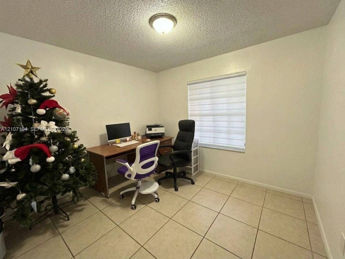 16259 SW 306th Street, #0, Homestead, Homestead, FL 33033 Neutral-toned room featuring large-format ceramic tile flooring, textured ceiling, flush-mount light fixture, and window with adjustable roller shade