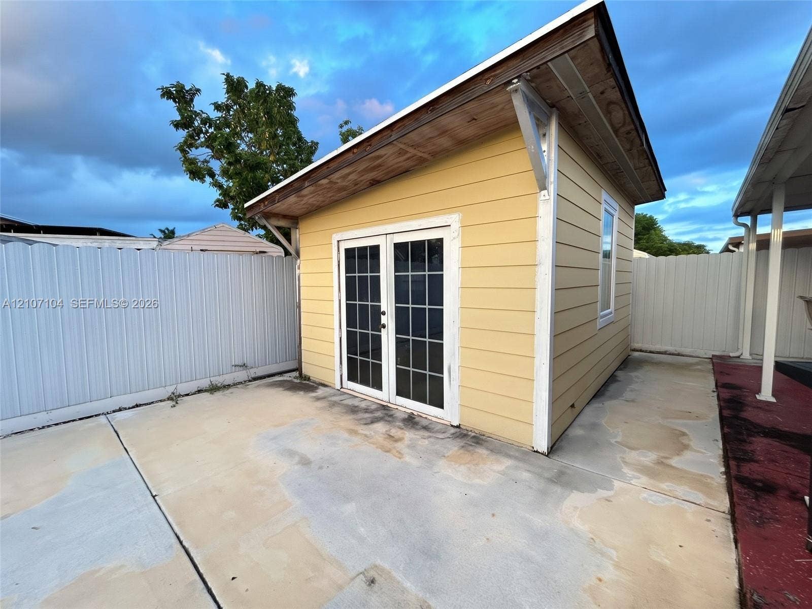 16259 SW 306th Street, #0, Homestead, Homestead, FL 33033 Detached structure featuring yellow horizontal lap siding, a single-slope roof, white-framed French doors with glass panes, and a concrete patio