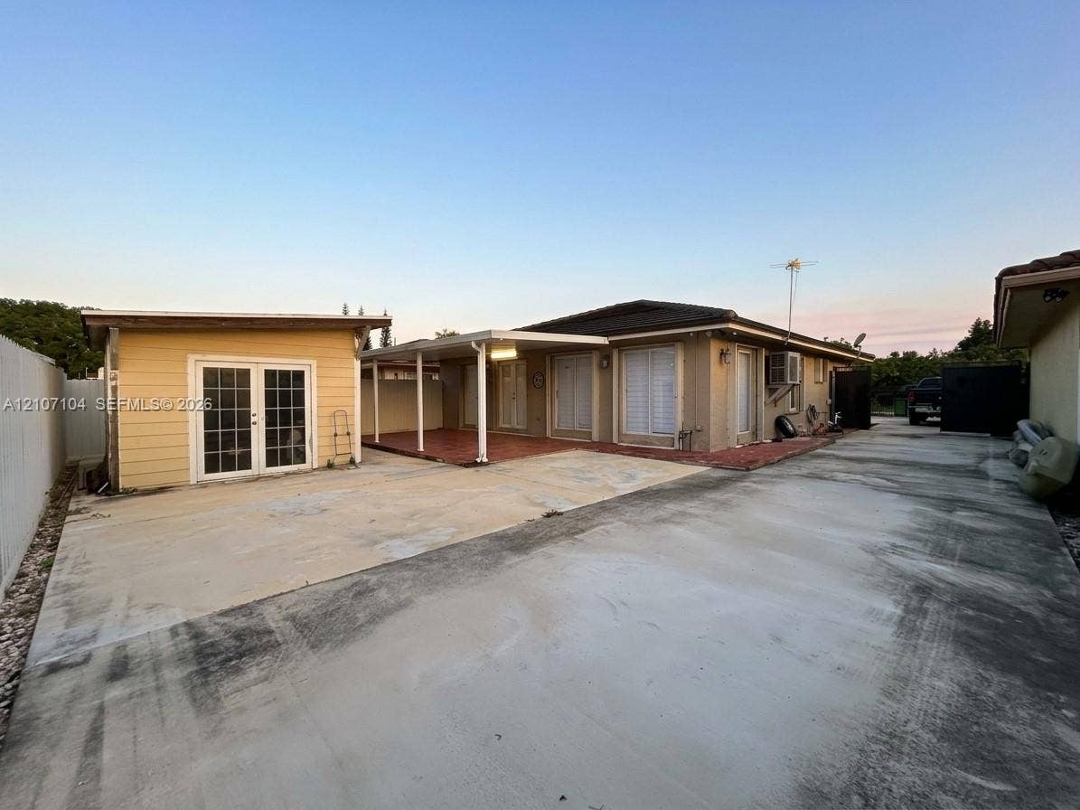 16259 SW 306th Street, #0, Homestead, Homestead, FL 33033 Concrete driveway, detached accessory structure with French doors, covered patio with tile flooring, and exterior wall-mounted lighting