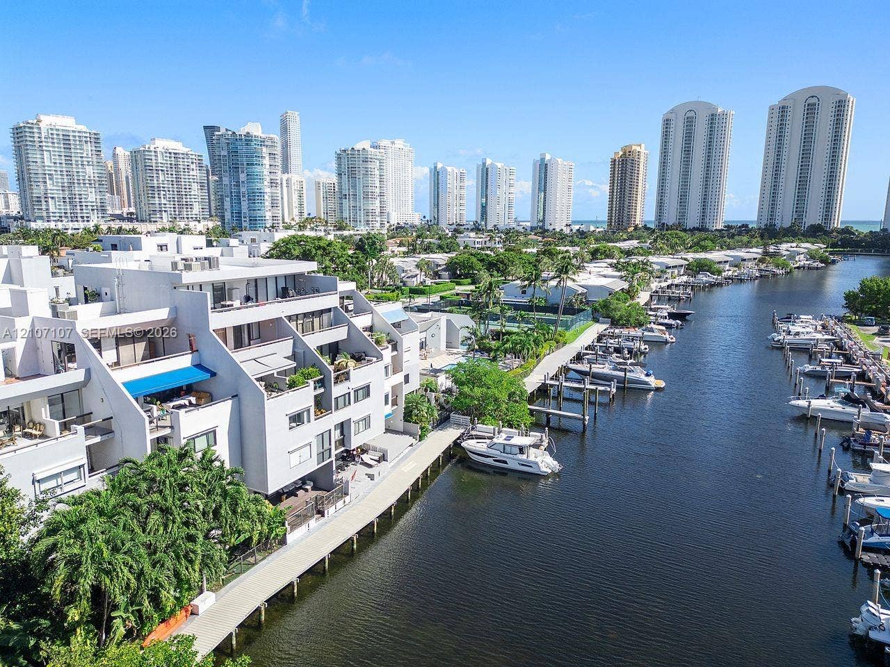 Waterfront multi-level residential structure featuring private boat slips, balconies with overhead sunshades, and concrete bulkhead walk