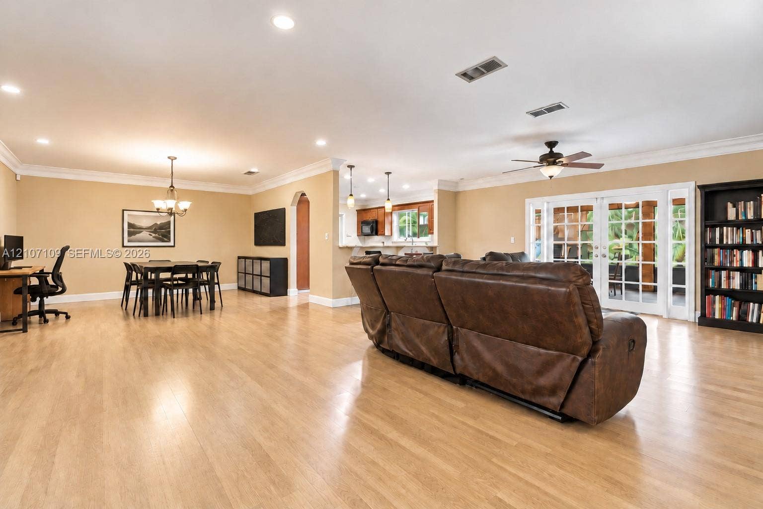 Open-concept interior featuring wood-finish flooring, crown molding, recessed lighting, and French doors
