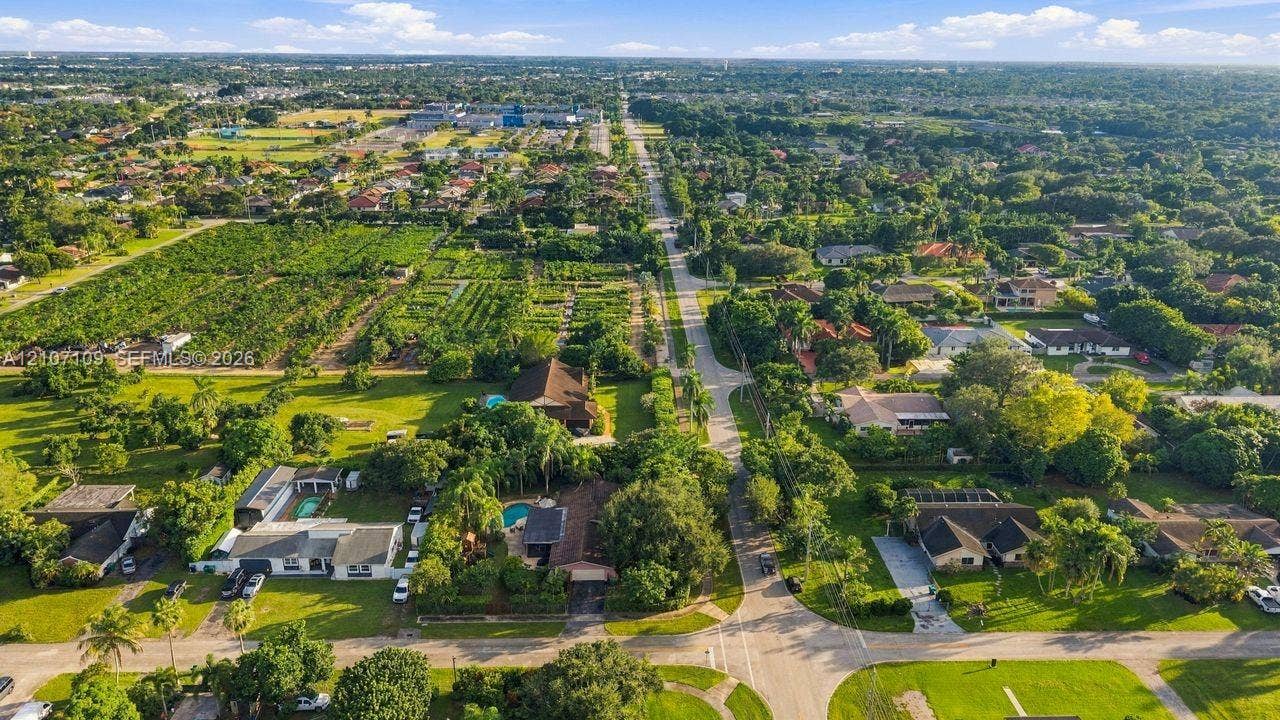 Aerial perspective featuring established residential lots, mature tree canopy, integrated swimming pools, and paved roadways