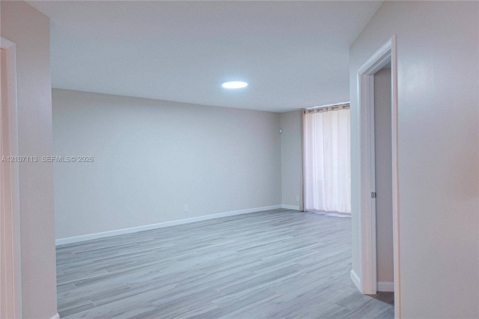 10451 W Broward Boulevard, #102, Plantation, Plantation, FL 33324 Neutral interior space featuring wood-finish flooring, a ceiling-mounted skylight, and a sliding glass door