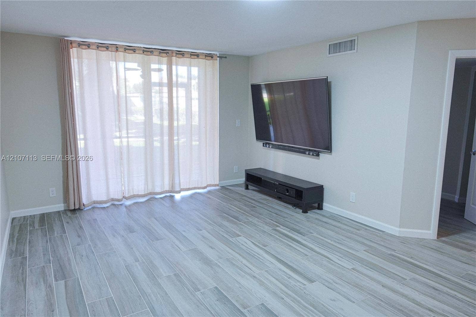 10451 W Broward Boulevard, #102, Plantation, Plantation, FL 33324 Wood-finish flooring, large sliding glass door, and neutral wall color