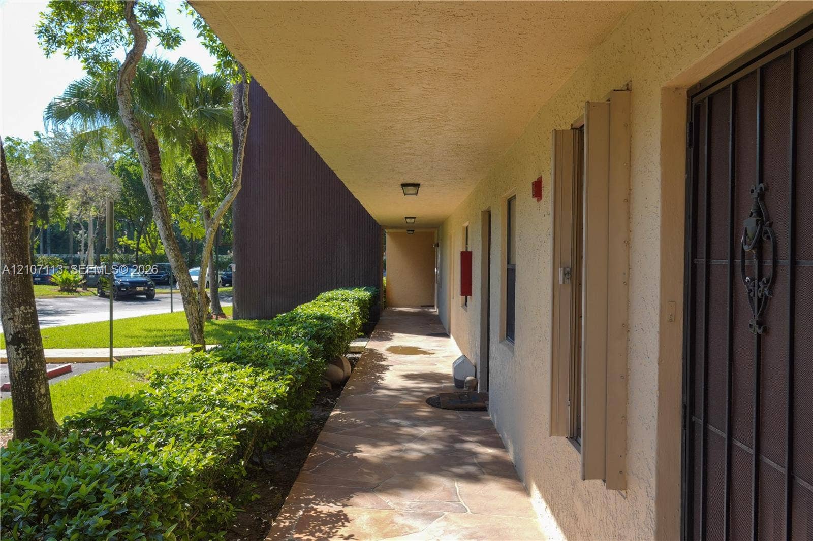 10451 W Broward Boulevard, #102, Plantation, Plantation, FL 33324 Covered exterior walkway featuring stone-finish flooring, stucco exterior wall, and metal security door