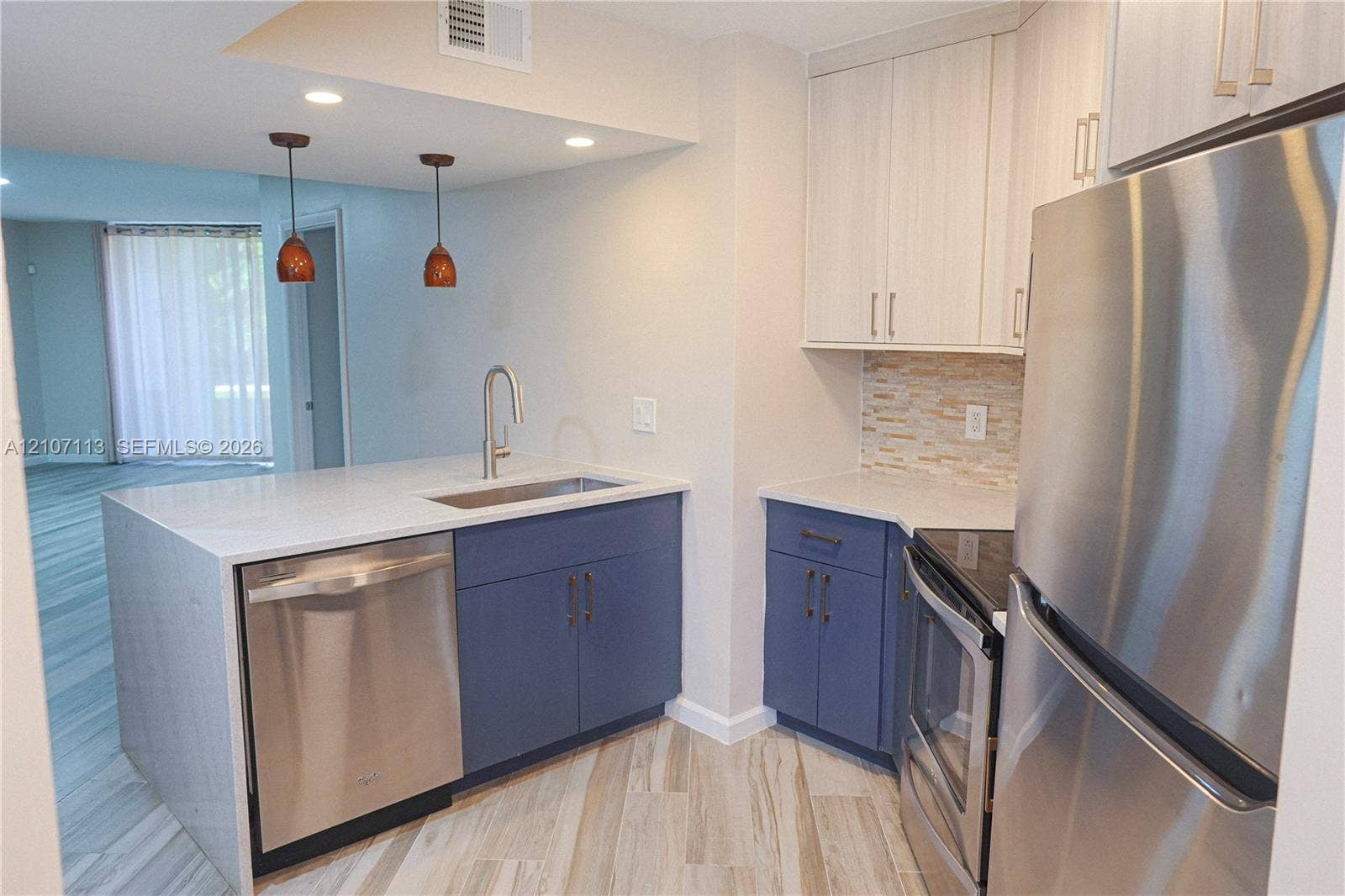 10451 W Broward Boulevard, #102, Plantation, Plantation, FL 33324 Kitchen featuring stainless steel appliances, dual-tone cabinetry, stone-style countertop, undermount sink with arched faucet, and stone-tiled backsplash