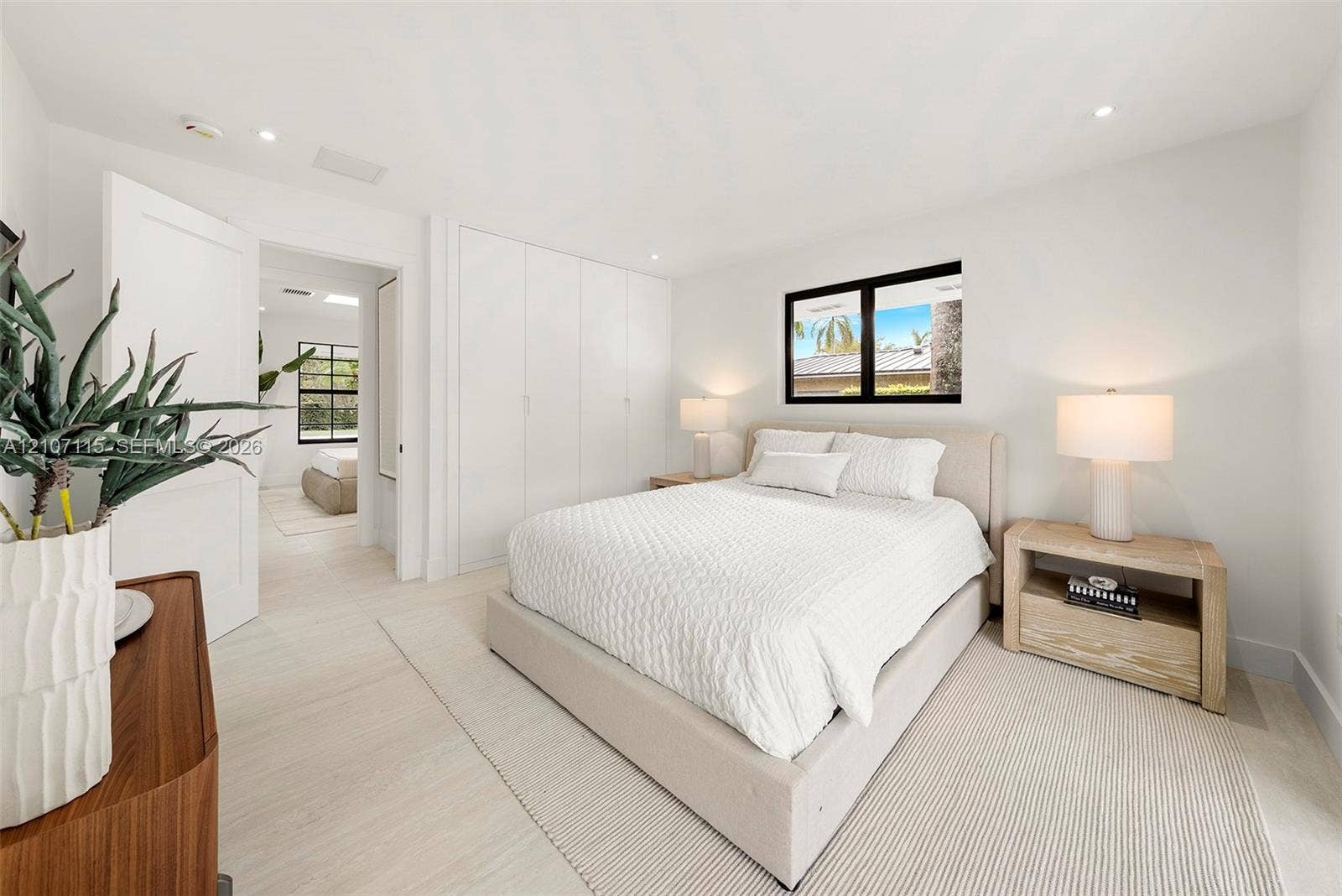 Bright room featuring recessed lighting, smooth-finish walls, wood-finish flooring, full-wall built-in cabinetry with flat-panel doors, and a black-frame window