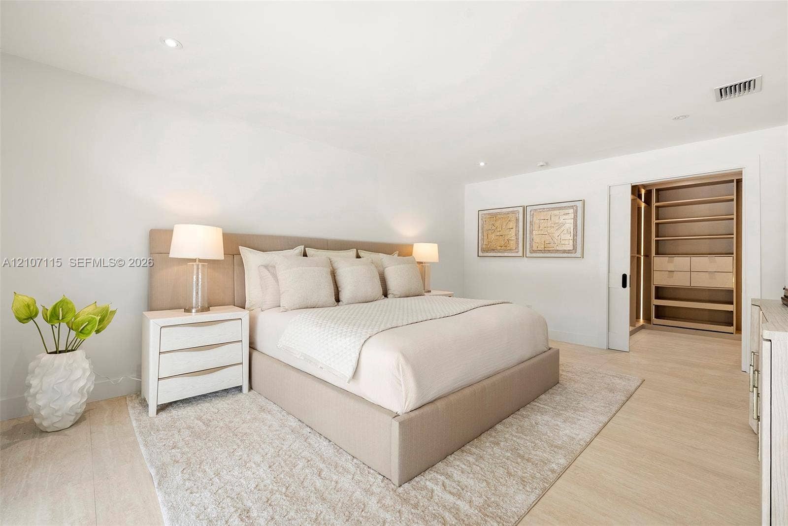Neutral-toned room featuring light-toned wood-finish flooring, recessed lighting, and a walk-in closet with built-in cabinetry accessed by a sliding pocket door