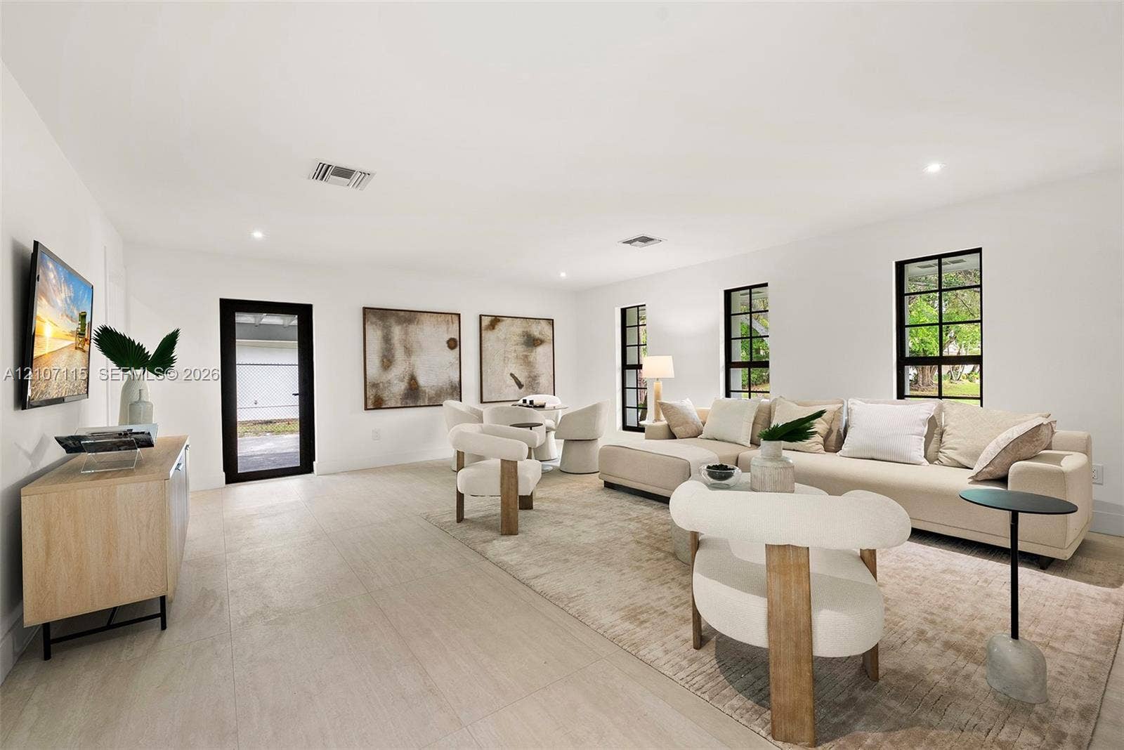 Open-concept living space featuring neutral wall-to-wall flooring, oversized windows with black frames, and recessed lighting