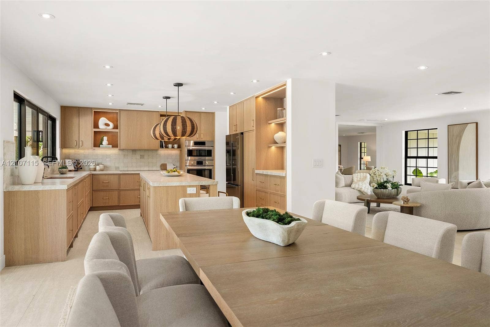 Custom wood cabinetry with integrated lighting, stone countertops, stainless steel built-in double ovens, recessed lighting, and large-format tile flooring