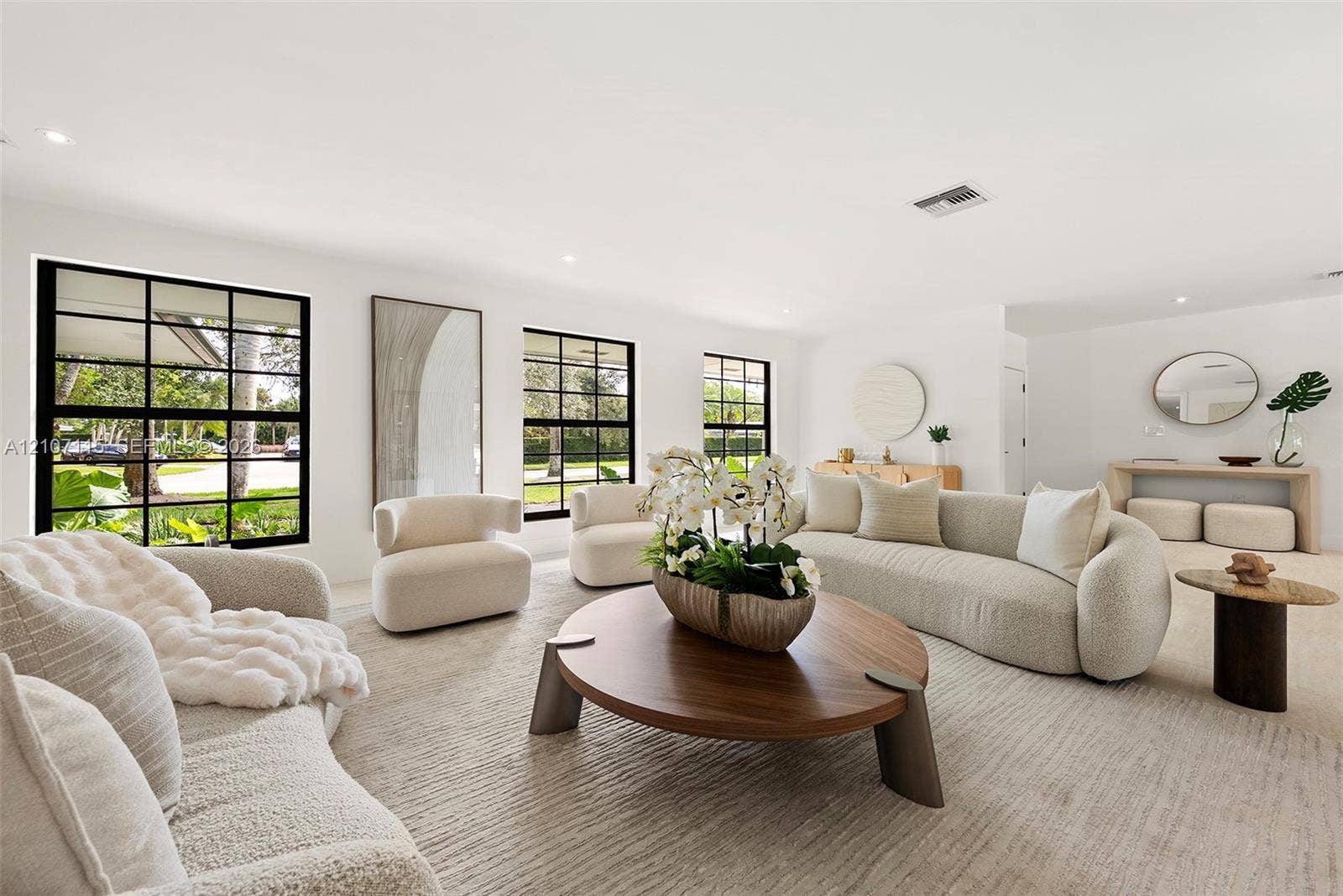 Open-concept living space featuring expansive windows with black mullions, recessed ceiling lighting, and neutral-toned wall-to-wall carpeting
