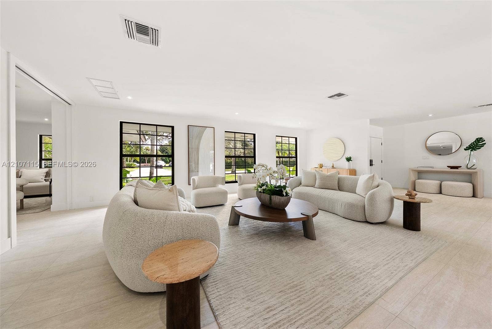 Open-concept interior featuring light-toned flooring, expansive grid-pattern windows with dark frames, and recessed lighting