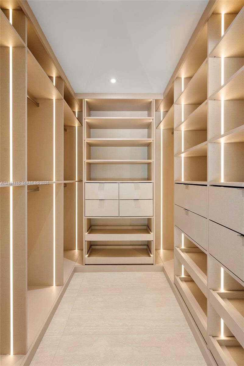Custom walk-in closet featuring floor-to-ceiling built-in cabinetry, integrated vertical LED strip lighting, modular shelving, and multi-drawer storage units