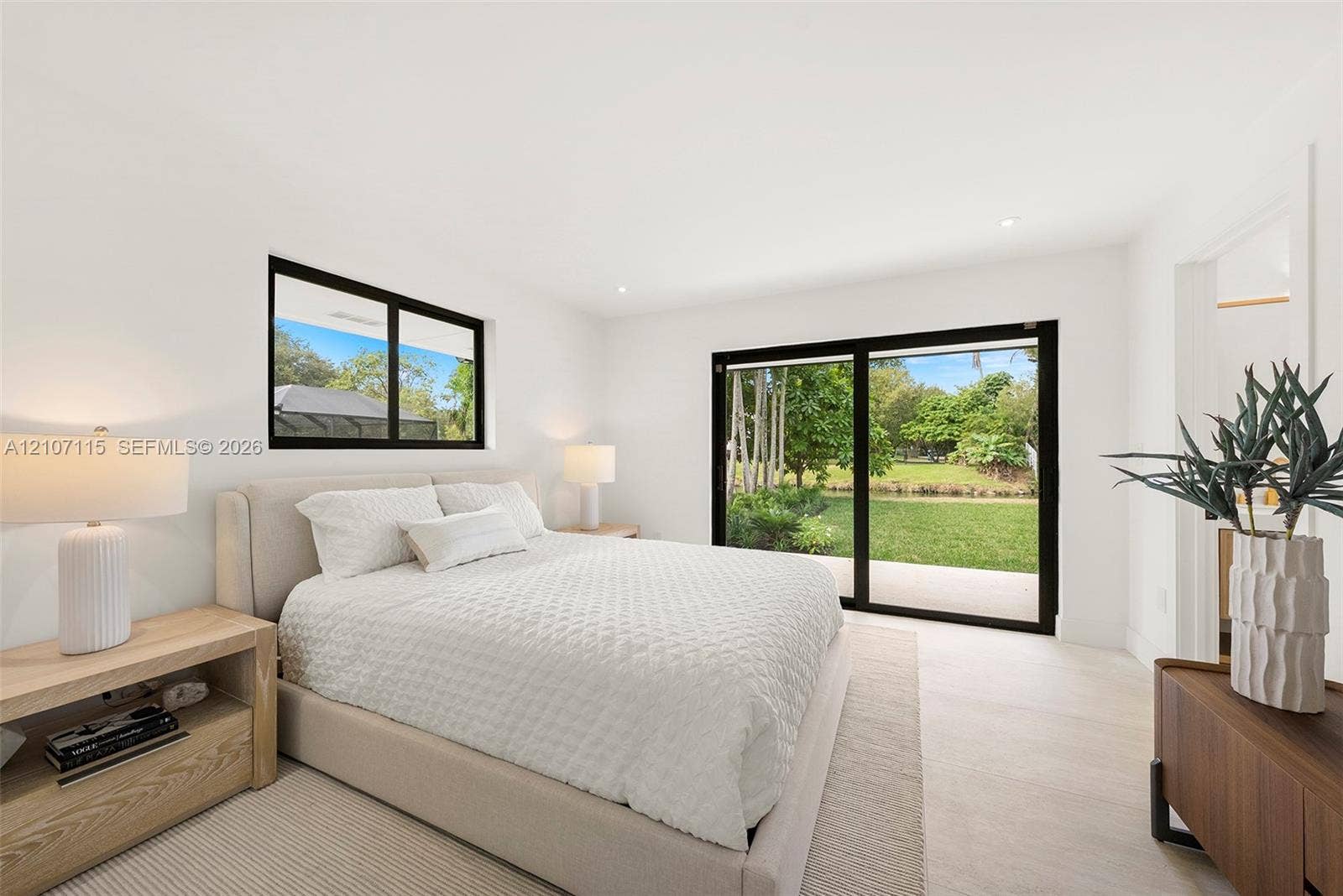 Suite Bedroom 1 ,Bright interior featuring neutral walls, large sliding glass doors, black-framed windows, and light-toned flooring