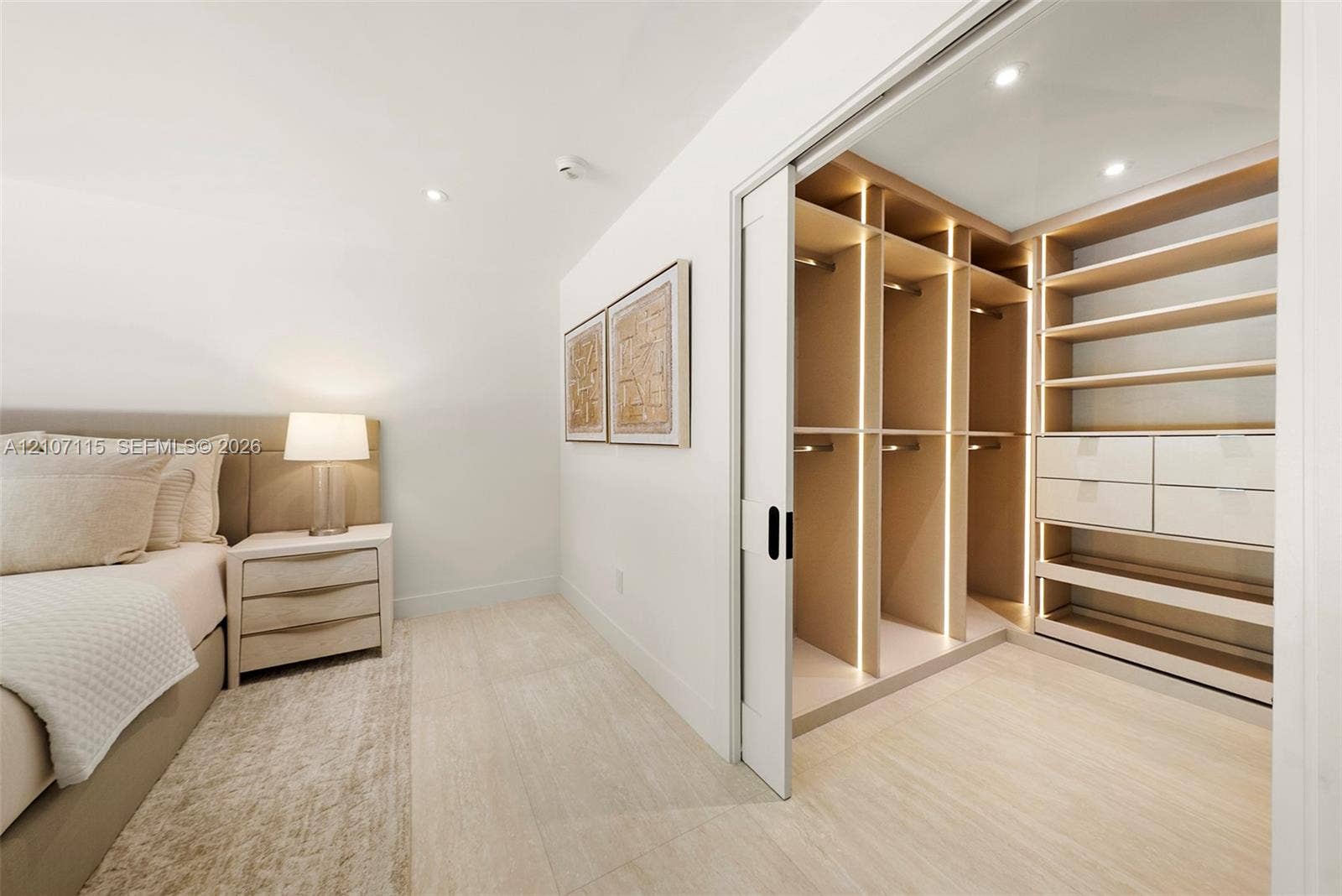 Walk-in closet featuring custom built-in cabinetry, integrated vertical lighting, polished drawers, open shelving, and a sliding door