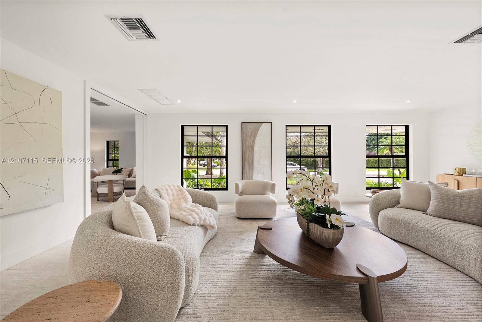 Spacious living area featuring large format tile flooring, black-framed multi-pane windows, and recessed lighting