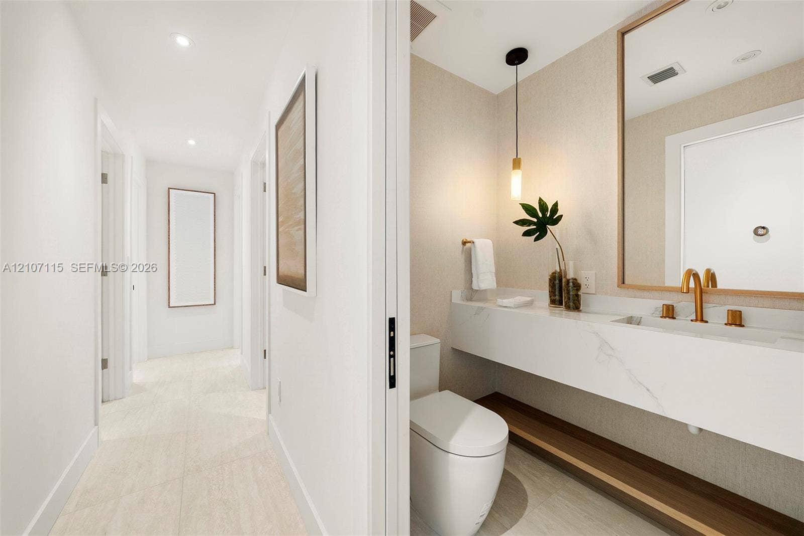 Powder room Floating vanity with stone-surfaced countertop, integrated rectangular sink, brass-finish fixtures, textured wall covering, and pendant lighting