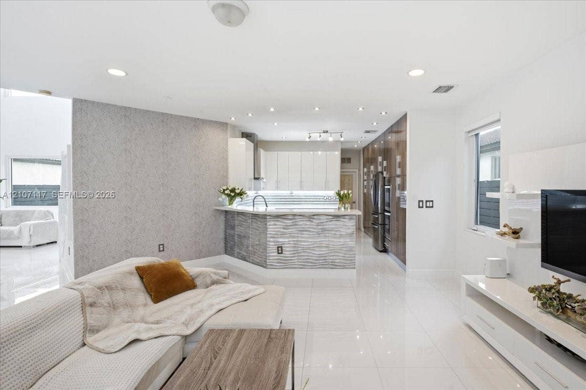 7863 NW 111th Court, Doral, FL 33178 Open-concept kitchen featuring high-gloss cabinetry, a textured stone-finish island, integrated stainless steel appliances, recessed ceiling lighting, and polished tile flooring