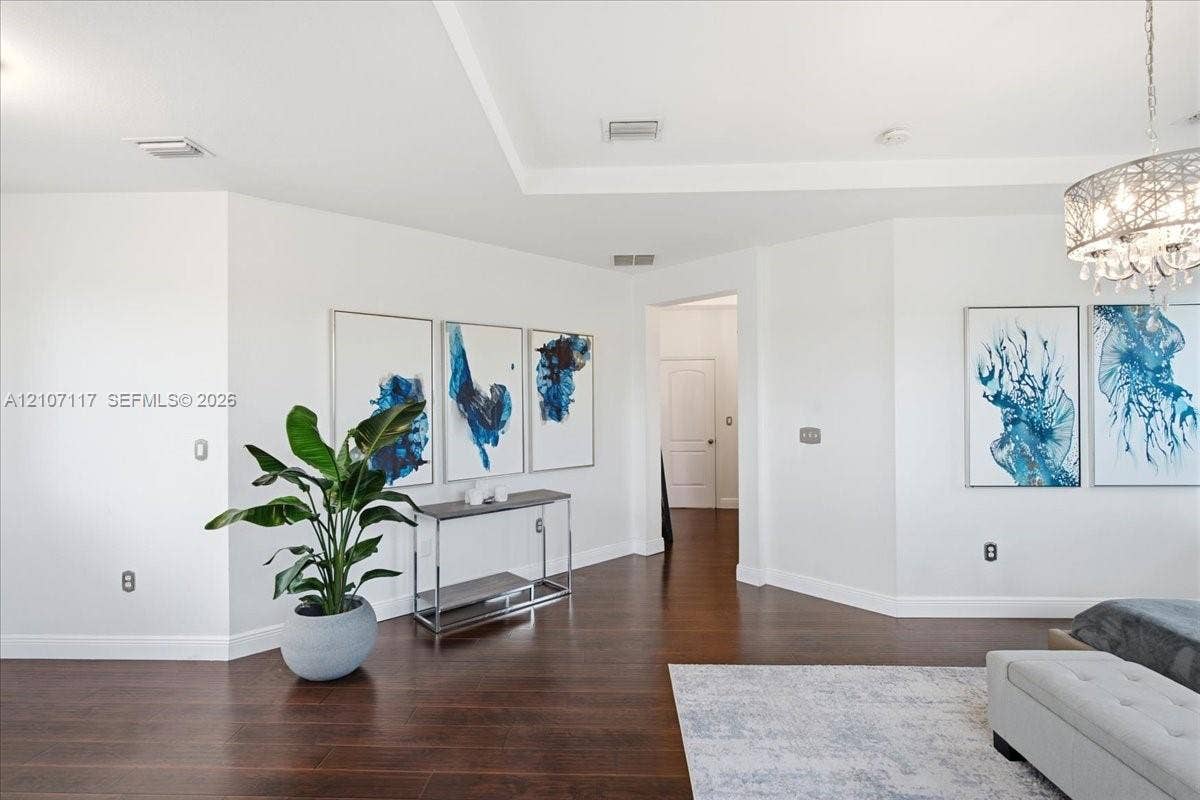 7863 NW 111th Court, Doral, FL 33178 Interior space featuring dark wood-finish flooring, recessed tray ceiling, and a decorative crystal-style chandelier