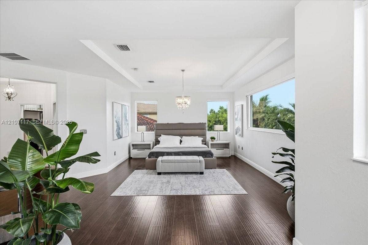 7863 NW 111th Court, Doral, FL 33178 Spacious room featuring wood-finish flooring, a recessed tray ceiling, large picture windows, and a crystal-style chandelier