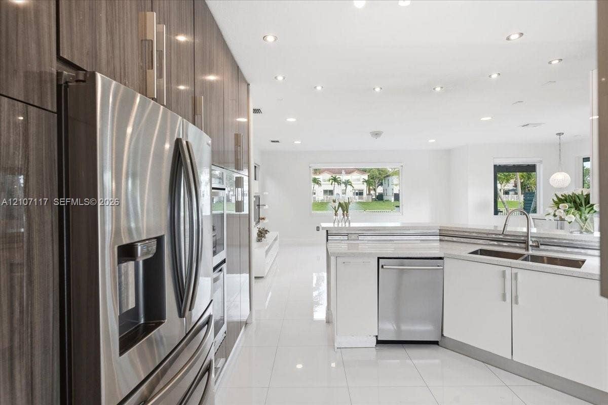 7863 NW 111th Court, Doral, FL 33178 Modern kitchen featuring high-gloss, wood-grain cabinetry, stainless steel appliances, white stone countertops, integrated recessed lighting, and large-format porcelain tile flooring