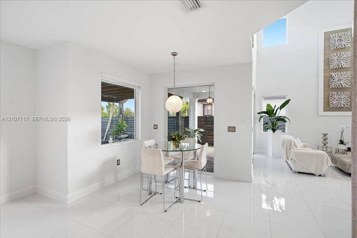 7863 NW 111th Court, Doral, FL 33178 Open-concept space featuring polished tile flooring, soaring vaulted ceilings, expansive windows, and a modern spherical pendant light fixture