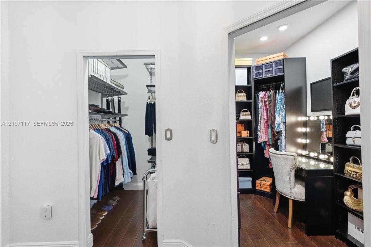 7863 NW 111th Court, Doral, FL 33178 Walk-in storage spaces featuring dark wood-finish flooring, built-in shelving units, integrated task lighting, and a built-in vanity