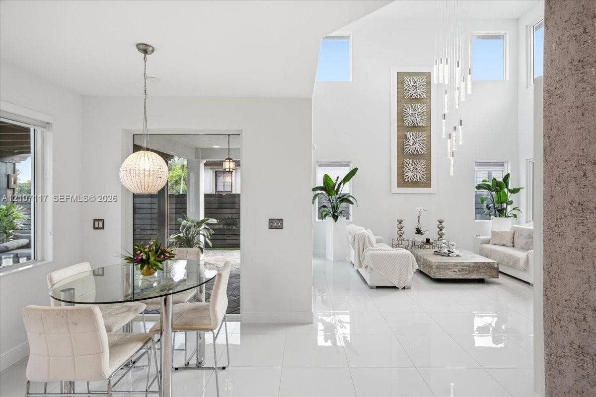 7863 NW 111th Court, Doral, FL 33178 High-ceilinged interior featuring polished tile flooring, multi-level hanging pendant lighting, and abundant natural light provided by clerestory windows