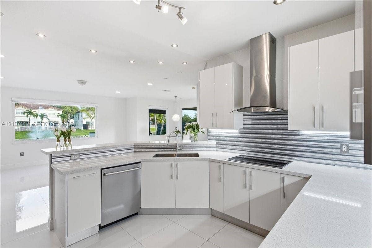 7863 NW 111th Court, Doral, FL 33178 Contemporary kitchen featuring flat-panel white cabinetry, light-toned countertops, a textured metal backsplash, stainless steel appliances, and large-format floor tiling
